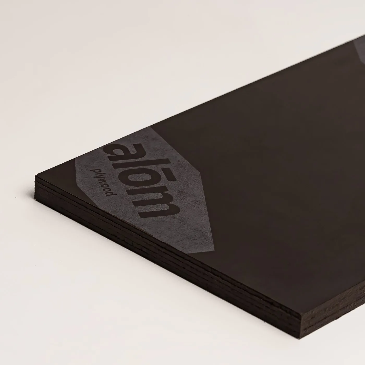 A close-up corner of a film-faced plywood sheet with the ALOM wrap mark
